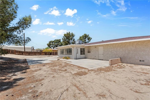 rear view of property with stucco siding, a patio, and fence