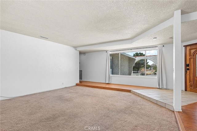 unfurnished living room featuring carpet floors, a textured ceiling, and visible vents