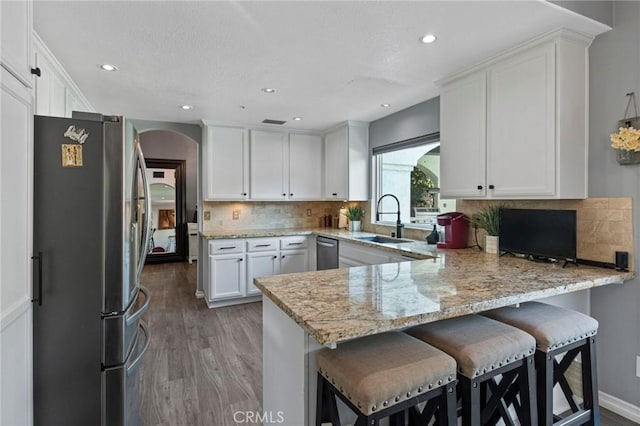 13656 Dronfield Ave, Sylmar, CA 91342 - kitchen with a peninsula, arched walkways, white cabinets, a sink, and stainless steel appliances
