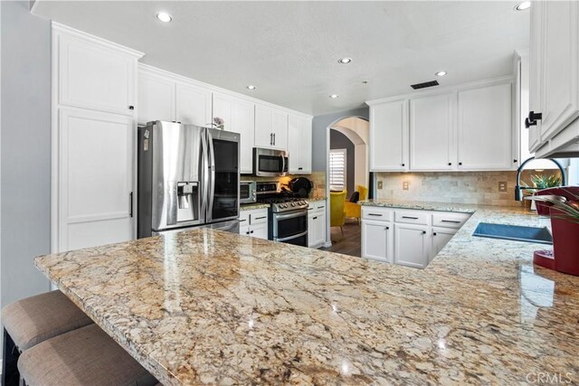 13656 Dronfield Ave, Sylmar, CA 91342 - kitchen with recessed lighting, appliances with stainless steel finishes, arched walkways, and light stone counters