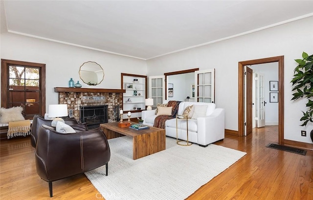 living room featuring baseboards, wood finished floors, visible vents, and a fireplace