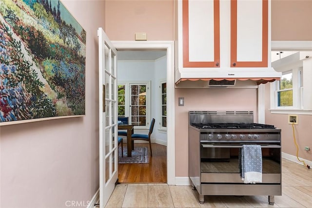 interior space with baseboards, gas stove, a wealth of natural light, and light tile patterned floors