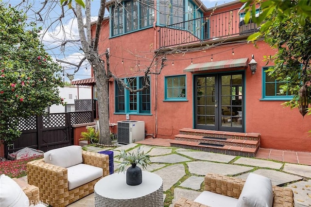 back of property with a balcony, french doors, a patio, entry steps, and stucco siding
