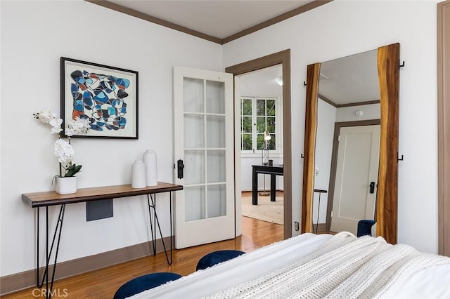 bedroom featuring baseboards, crown molding, french doors, and wood finished floors