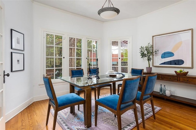 dining room with light wood-style floors, baseboards, and ornamental molding
