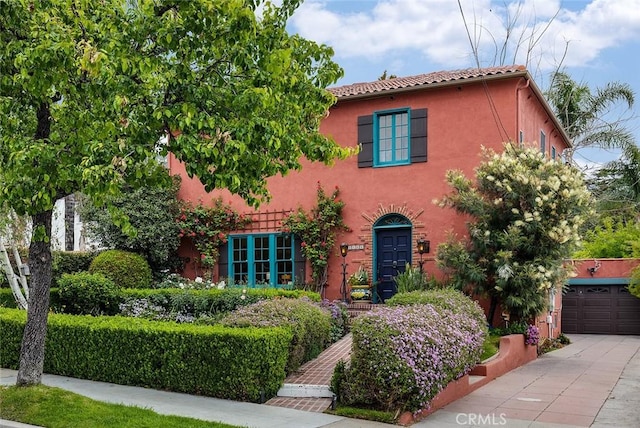 mediterranean / spanish-style house with a tiled roof, driveway, and stucco siding