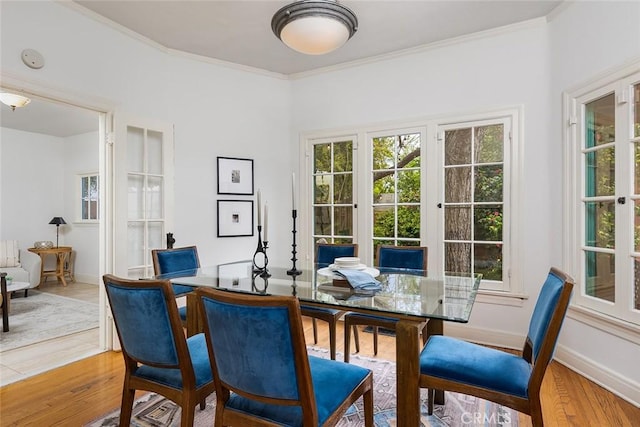 dining area with ornamental molding, light wood-style flooring, and plenty of natural light