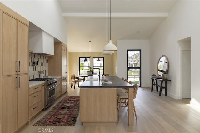459 E 18th St, Costa Mesa, CA 92627 - kitchen with high end stainless steel range, an island with sink, light brown cabinetry, a kitchen bar, and light wood-style floors