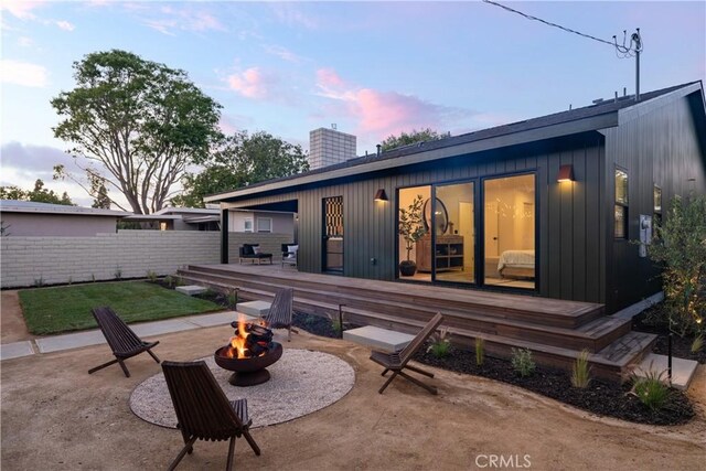 459 E 18th St, Costa Mesa, CA 92627 - back of house at dusk with an outdoor fire pit, a deck, a chimney, and a patio area