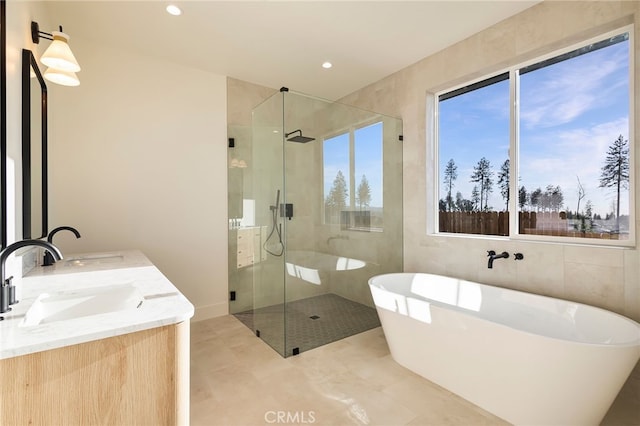 full bath featuring a shower stall, a freestanding bath, and a sink