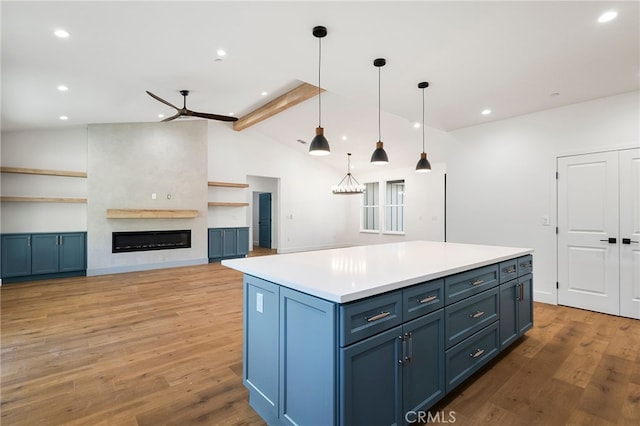 kitchen featuring light wood-style floors, ceiling fan, a kitchen island, recessed lighting, and vaulted ceiling with beams