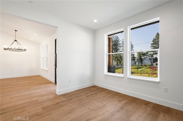 empty room with recessed lighting, an inviting chandelier, vaulted ceiling, light wood finished floors, and baseboards