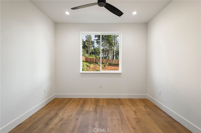 empty room with wood finished floors, a ceiling fan, recessed lighting, and baseboards