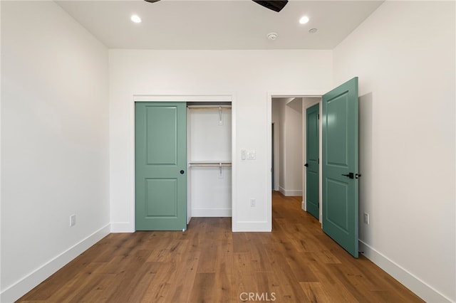 unfurnished bedroom featuring recessed lighting, a closet, wood finished floors, and baseboards