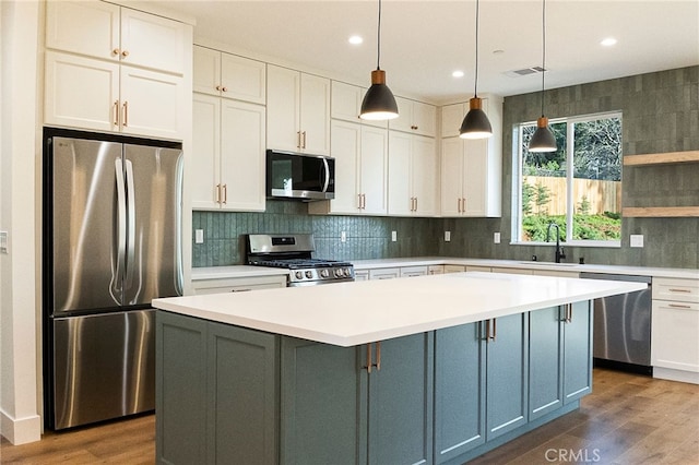 kitchen featuring wood finished floors, stainless steel appliances, light countertops, and visible vents