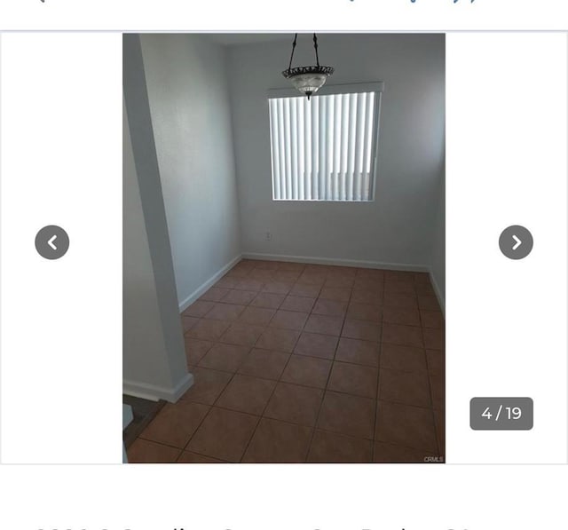 empty room featuring baseboards and tile patterned flooring