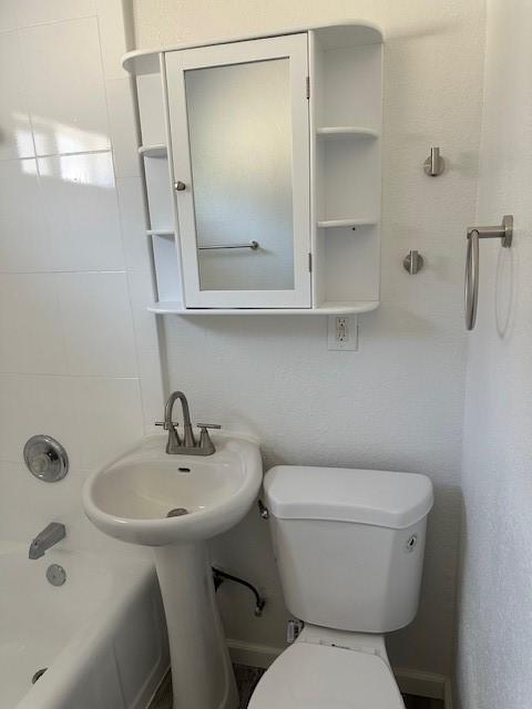 bathroom featuring shower / washtub combination and toilet