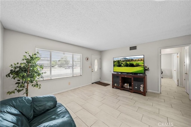 living area with a textured ceiling, visible vents, baseboards, and light tile patterned floors