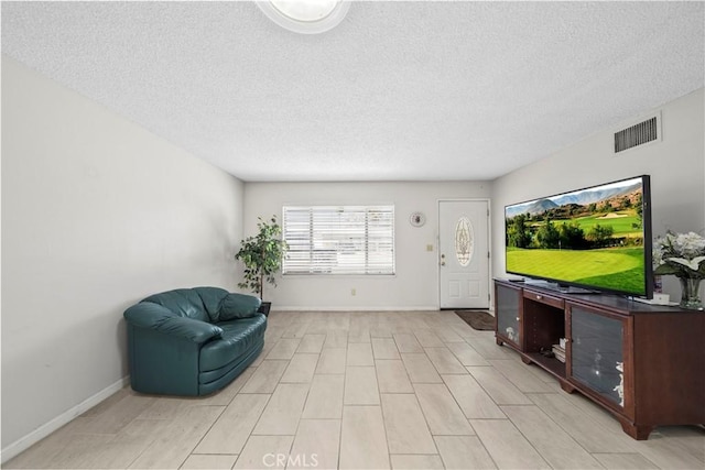 sitting room featuring baseboards, a textured ceiling, and visible vents