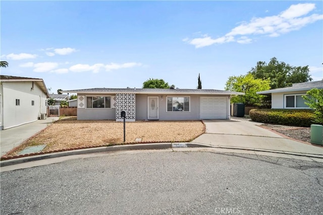 ranch-style house featuring stucco siding, an attached garage, driveway, and fence