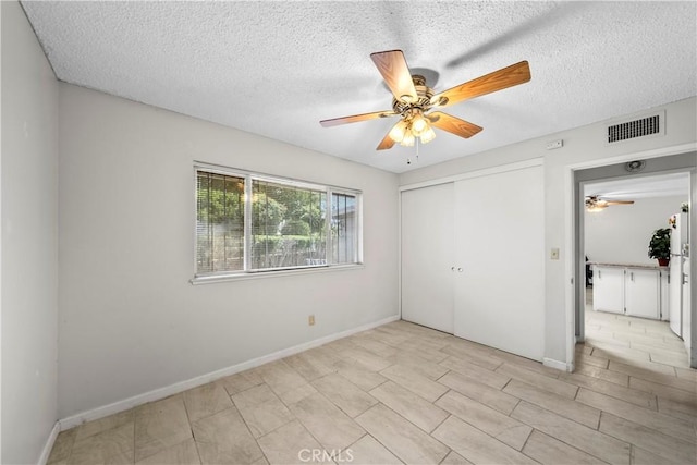 unfurnished bedroom with baseboards, a textured ceiling, visible vents, and a closet