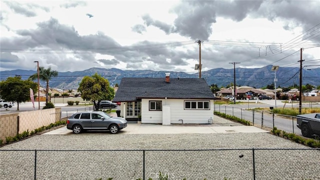 rear view of property featuring a mountain view, fence, and driveway