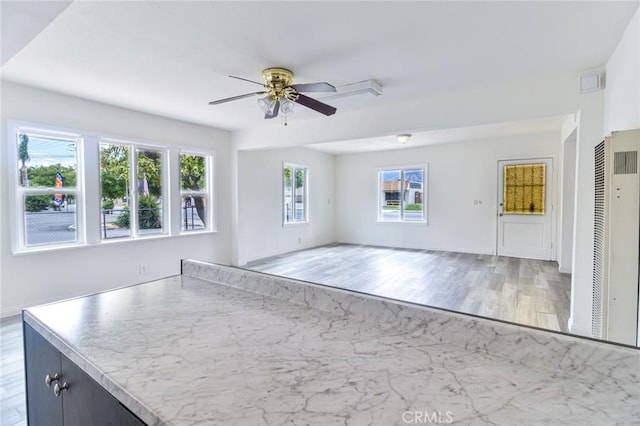 unfurnished living room featuring a heating unit, ceiling fan, and light wood-type flooring