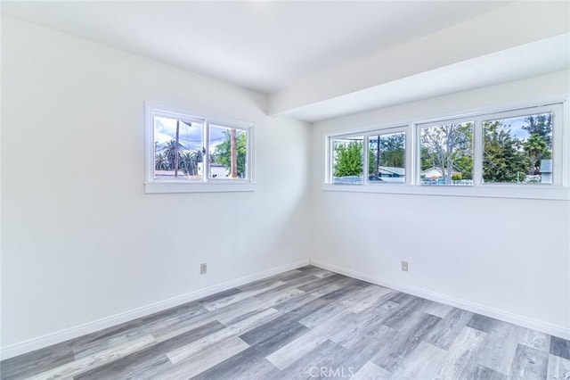 spare room with light wood-type flooring and baseboards