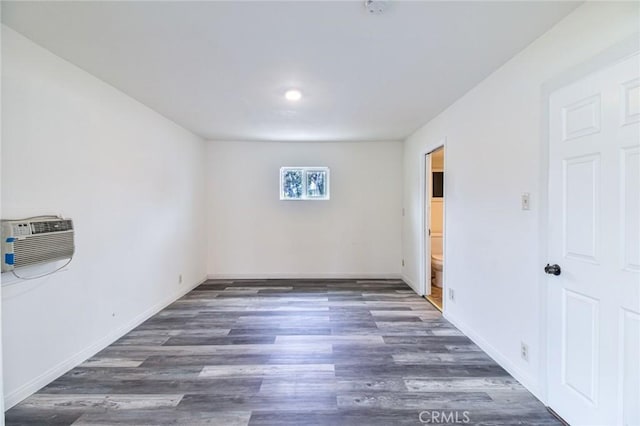 unfurnished room featuring a wall mounted AC, wood finished floors, and baseboards