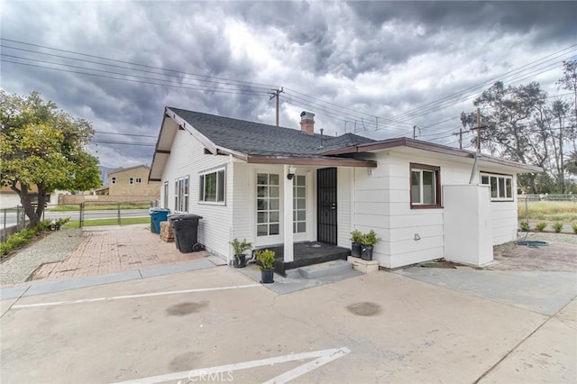 bungalow-style house with a chimney, fence, and a patio area