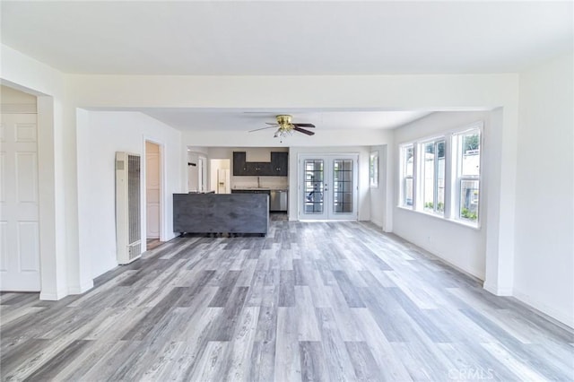 unfurnished living room featuring a heating unit, wood finished floors, plenty of natural light, and baseboards