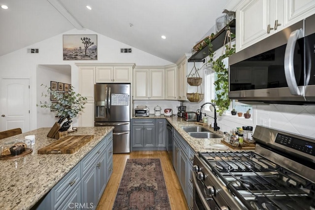 kitchen featuring a sink, light wood-type flooring, stainless steel appliances, gray cabinetry, and visible vents