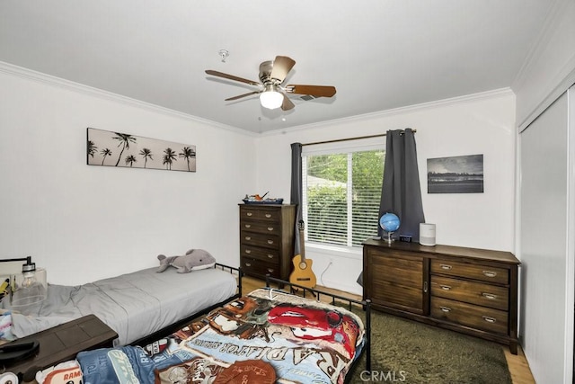 bedroom with a ceiling fan, crown molding, wood finished floors, and a closet