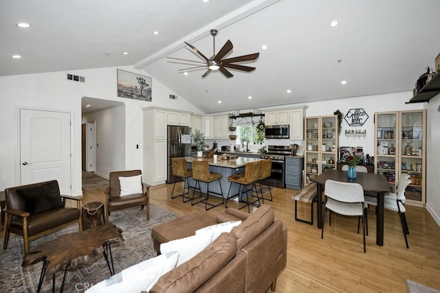living room with ceiling fan, beamed ceiling, light wood-style floors, and visible vents