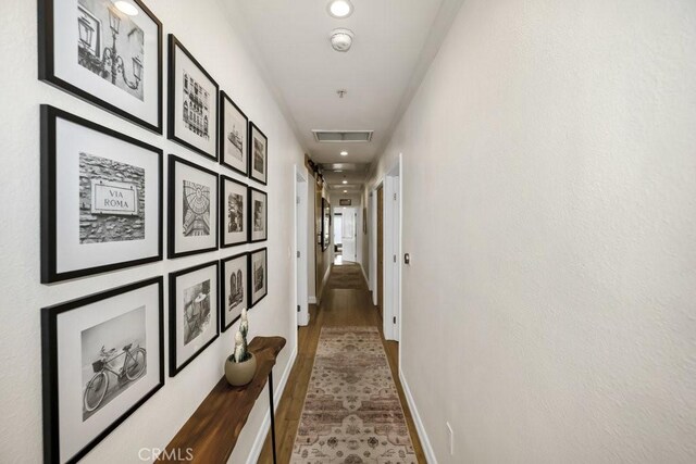 hall with visible vents, baseboards, wood finished floors, and recessed lighting