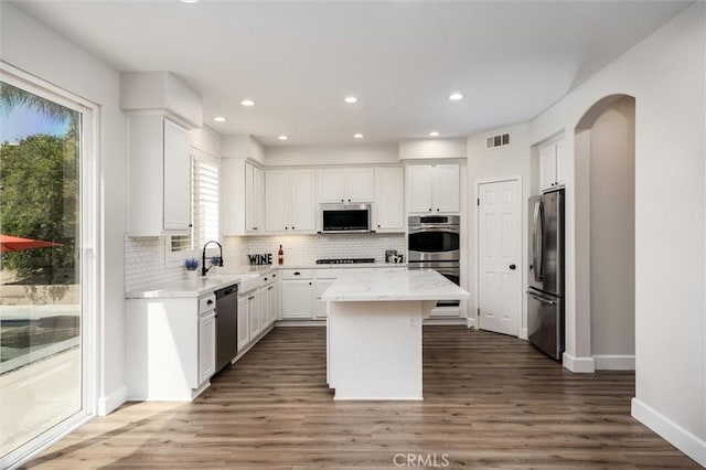 30461 Savoie St, Murrieta, CA 92563 - kitchen with appliances with stainless steel finishes, a center island, white cabinetry, tasteful backsplash, and visible vents
