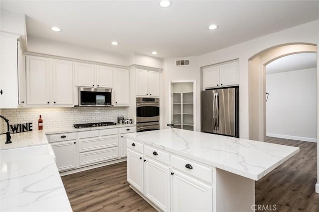 30461 Savoie St, Murrieta, CA 92563 - kitchen featuring visible vents, arched walkways, tasteful backsplash, stainless steel appliances, and dark wood-type flooring
