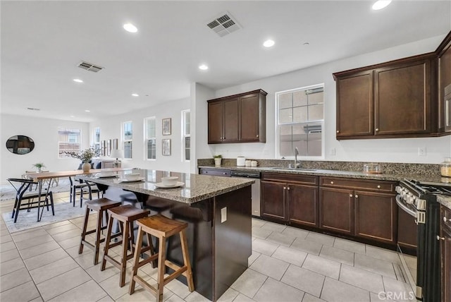 kitchen with appliances with stainless steel finishes, dark stone countertops, visible vents, and light tile patterned floors