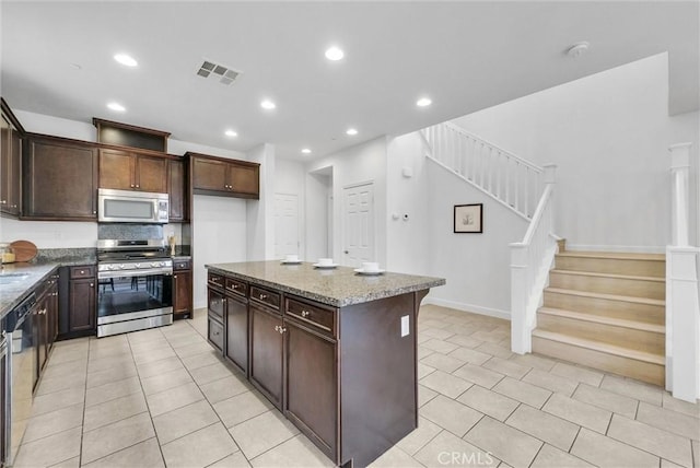 2882 E Via Terrano, Ontario, CA 91764 - kitchen with appliances with stainless steel finishes, light tile patterned floors, stone countertops, recessed lighting, and dark brown cabinetry