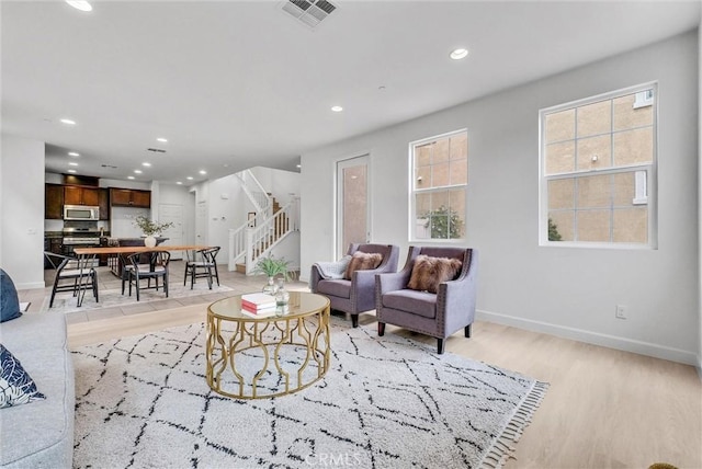 living room with baseboards, visible vents, recessed lighting, light wood-style floors, and stairway