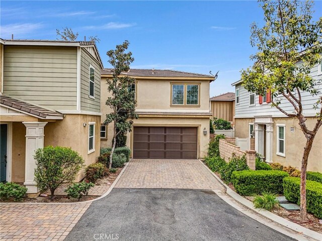 view of front of property featuring stucco siding, fence, aphalt driveway, and a garage