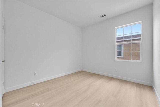 spare room with baseboards, light wood-style flooring, and visible vents