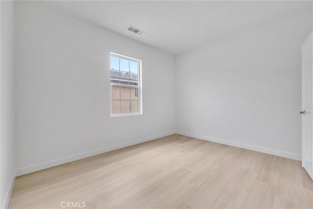 spare room featuring wood finished floors, visible vents, and baseboards
