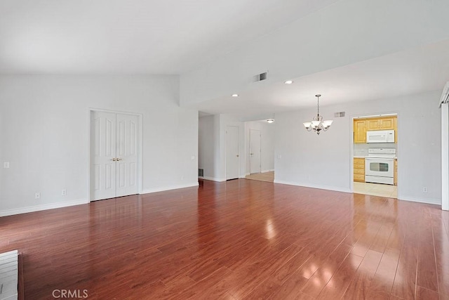 unfurnished living room featuring lofted ceiling, wood finished floors, a chandelier, and visible vents