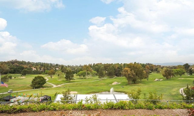view of property's community with a lawn, fence, a water view, and golf course view