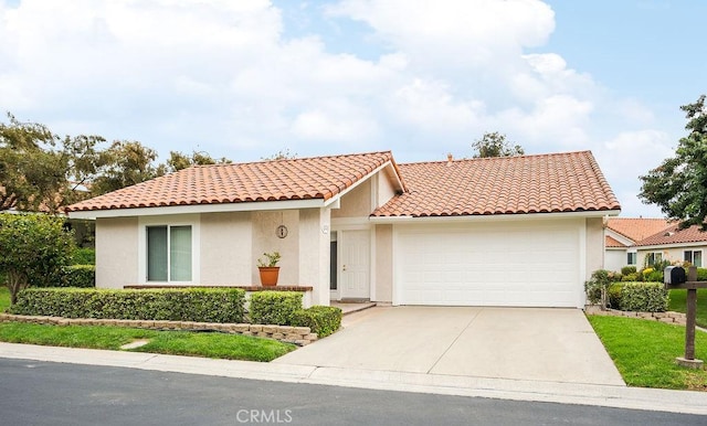 mediterranean / spanish-style house with an attached garage, concrete driveway, a tiled roof, and stucco siding