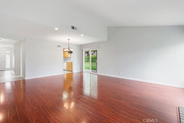 unfurnished living room featuring wood finished floors, a sink, a chandelier, baseboards, and visible vents
