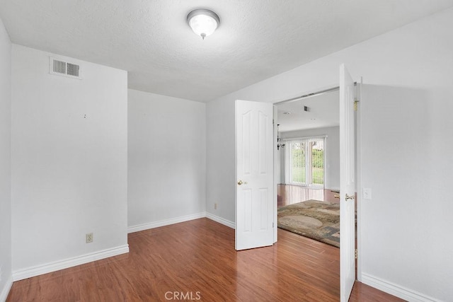 spare room with baseboards, wood finished floors, and visible vents
