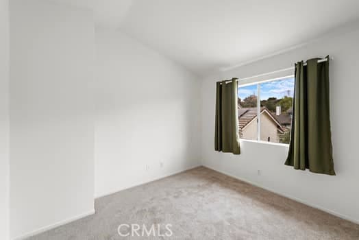 empty room with carpet flooring and vaulted ceiling
