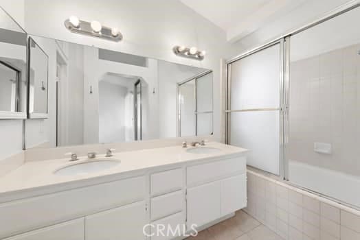 full bathroom featuring a sink, tile patterned flooring, tiled shower / bath combo, and double vanity